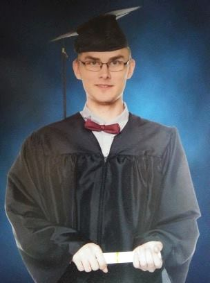Photo of Noah Russell, a young white man with glasses. He is wearing a graduation cap and gown.
