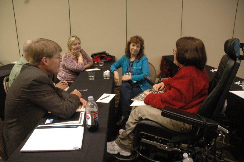 Pseron in mobility chair discussing workshop with 4 others